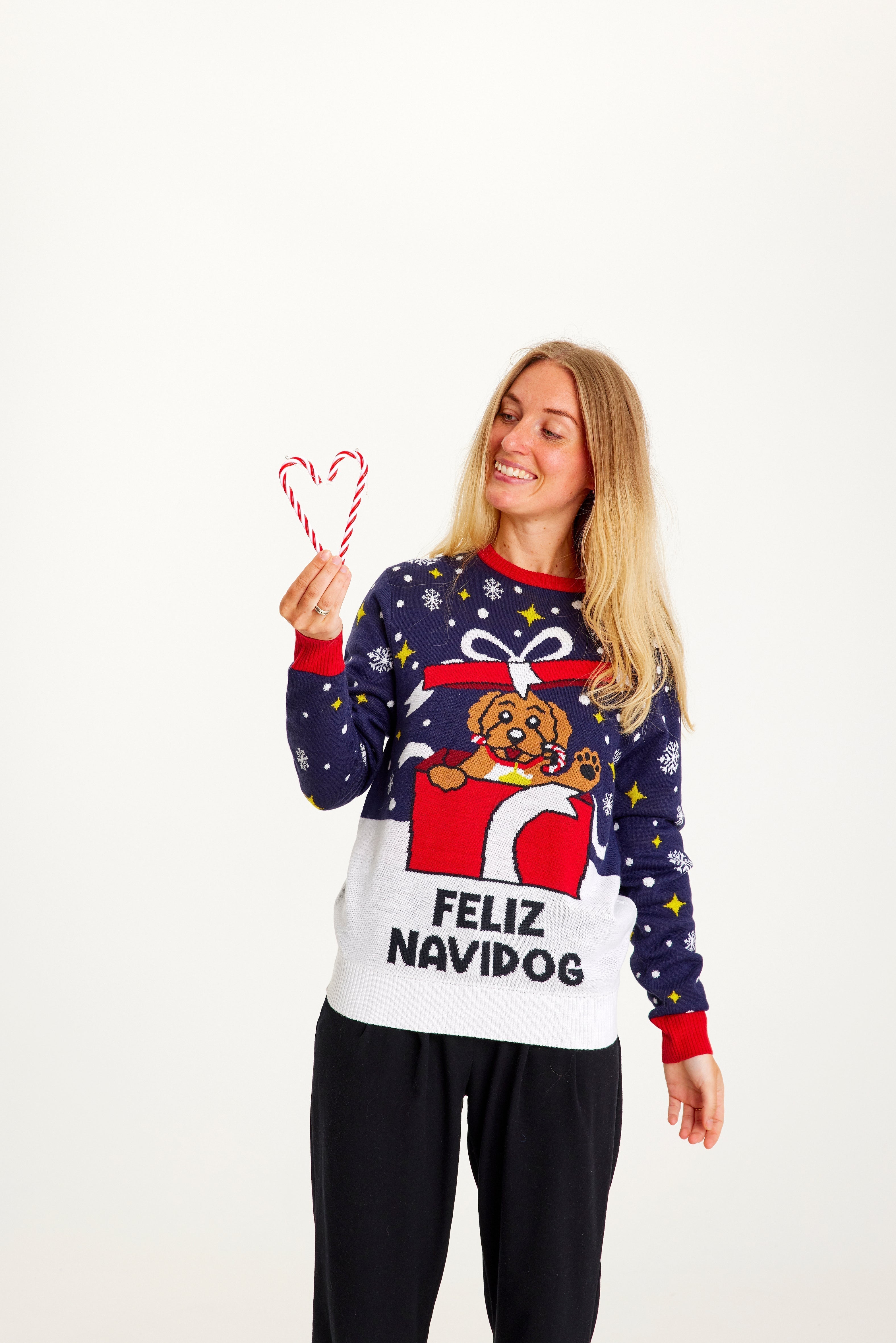 Una donna posa indossando un maglione natalizio blu.